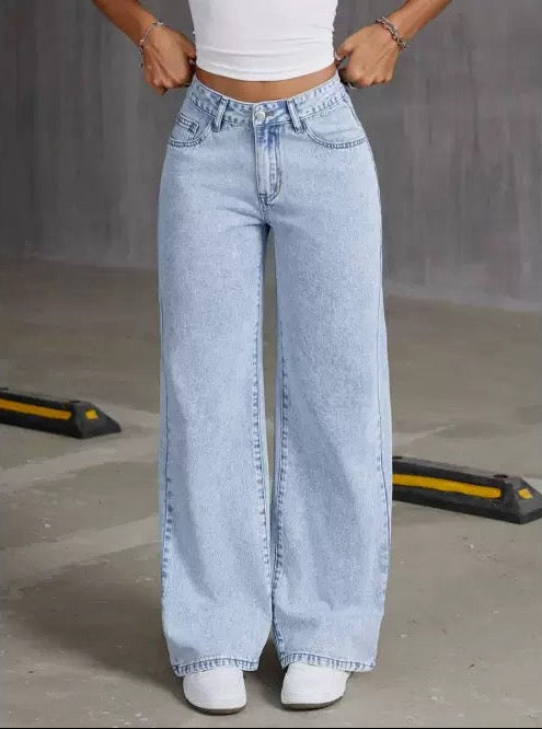 Person wearing light blue wide-leg jeans and a white crop top in an urban setting.